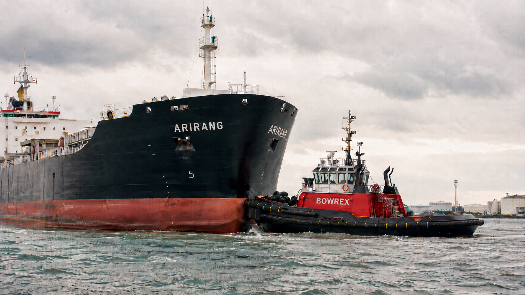 Tugboat pushing the bow of a commercial vessel
